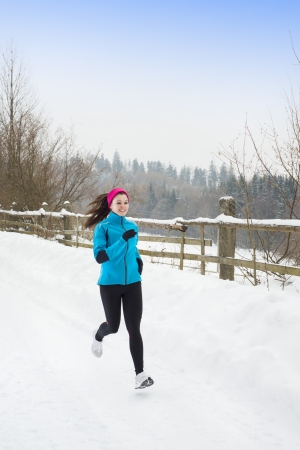 Athlete woman is running during winter training outside in cold snow weather.の写真素材