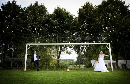 Bride and groom are playing at the football pitchの写真素材