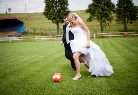 Bride and groom are playing at the football pitchの写真素材