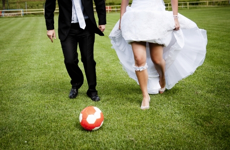 Bride and groom are playing at the football pitchの写真素材