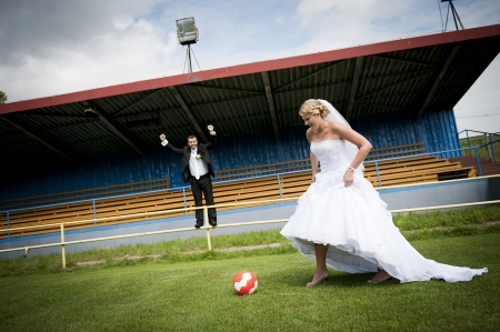 Bride and groom are playing at the football pitchの写真素材