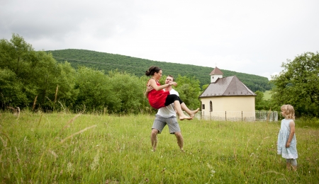Happy family is playing together in a green meadow.の写真素材