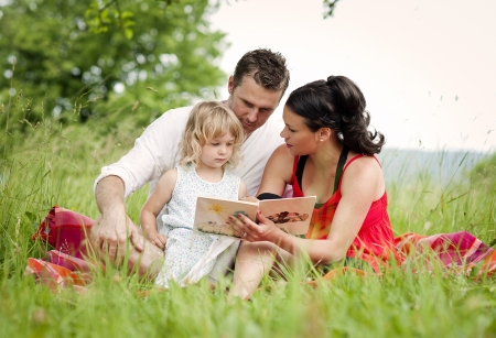 Happy family is playing together in a green meadow.の写真素材