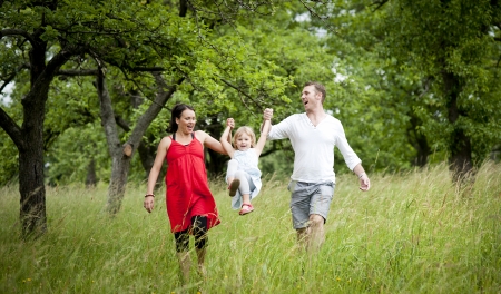 Happy family is playing together in a green meadow.の写真素材