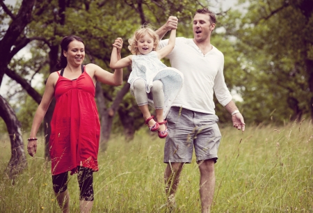 Happy family is playing together in a green meadow.の写真素材