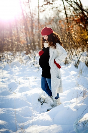 A beautiful pregnant woman is playing outside in the snowの写真素材