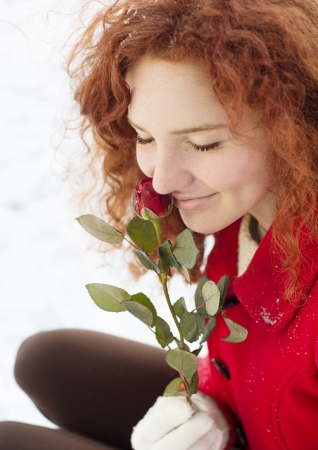 Beautiful girl with roses in the snow in winterの写真素材