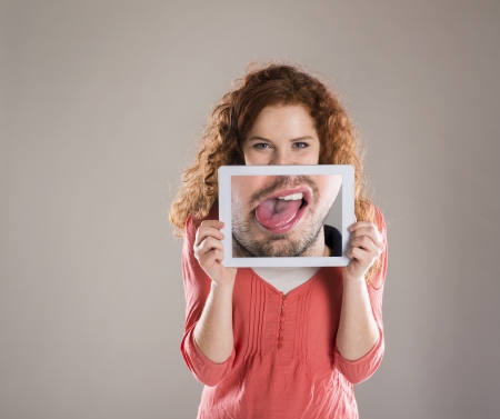 Funny studio portraits with tablet on isolated backgroundの写真素材
