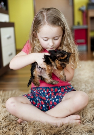 Little girl is playing with her puppy at homeの写真素材