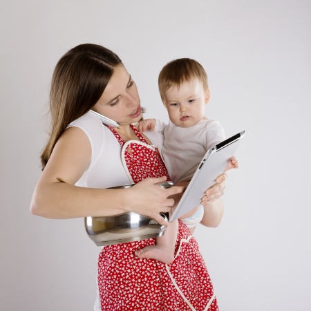 Young mother is looking at tablet with her baby Young mother is looking at tablet with her baby
