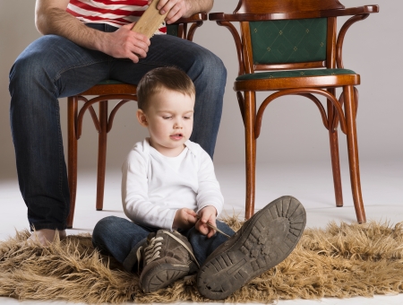 Child is putting on a big father s shoe の写真素材