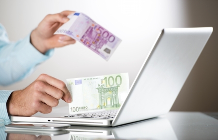 Businessman with laptop and money in his officeの写真素材