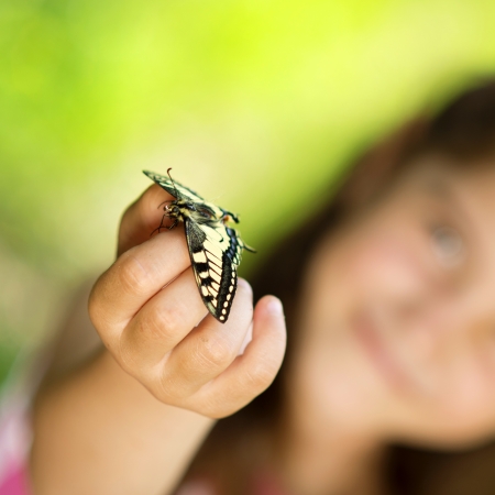 Little girl is playing with butterfly in natureの写真素材