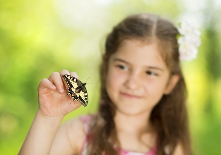 Little girl is playing with butterfly in natureの写真素材