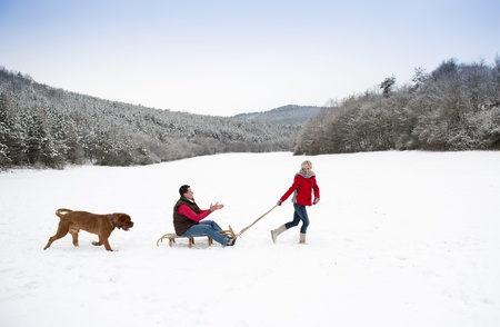Woman and man are having walk with dog in winter snowy countrysideの写真素材