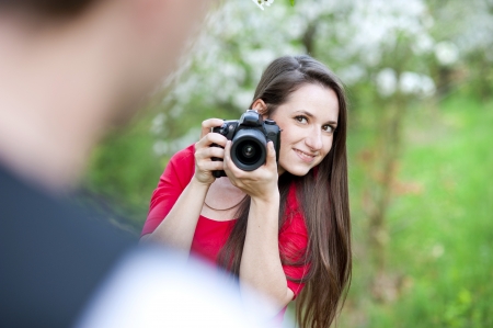 Photographer woman is taking photos in green parkの写真素材