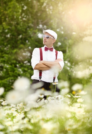 Portrait of handsome groom in the dandelion flower field in green park の写真素材