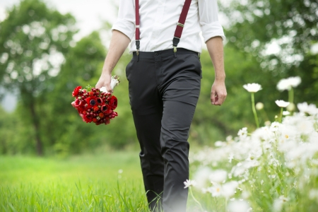Portrait of handsome groom in the dandelion flower field in green park の写真素材