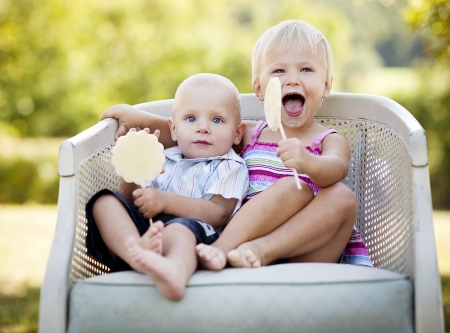 Two happy kids eating lolly in the parkの写真素材