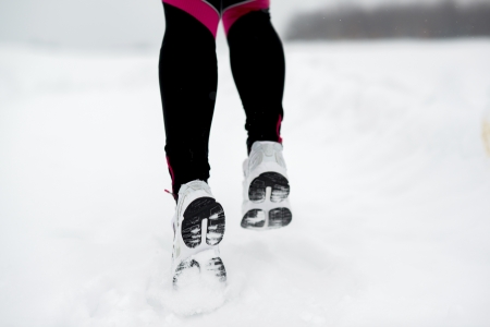 Athlete woman is running during winter training outside in cold snow weather の写真素材