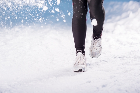 Athlete woman is running during winter training outside in cold snow weather の写真素材