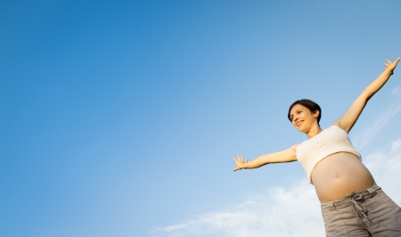 Portrait of young pregnant woman with a blue skyの写真素材