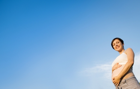 Portrait of young pregnant woman with a blue skyの写真素材