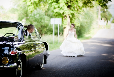 Happy bride and groom in a black car on wedding dayの写真素材