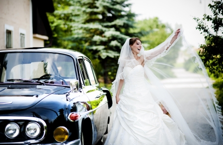 Happy bride and groom in a black car on wedding dayの写真素材