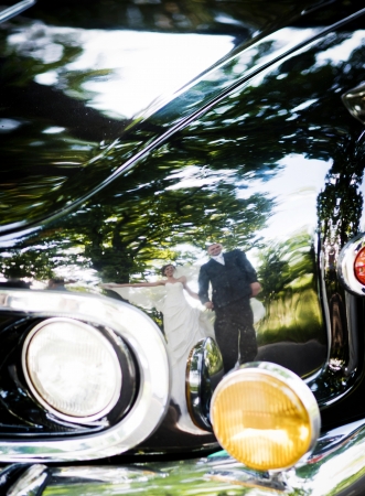 Happy bride and groom in a black car on wedding dayの写真素材