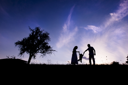 Silhouettes of happy parents having fun with their childrenの写真素材