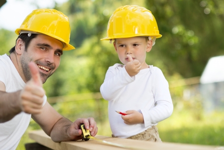 Little son helping his father with building workの写真素材