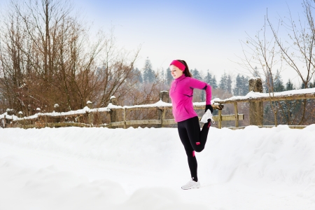 Athlete woman is running during winter training outside in cold snow weather の写真素材