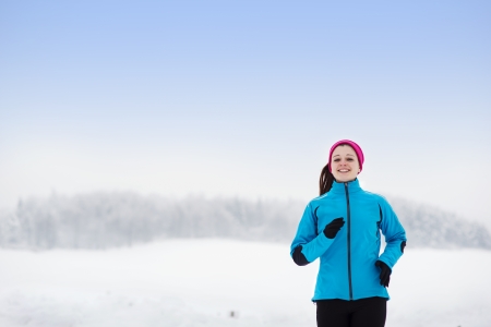 Athlete woman is running during winter in cold snow weather の写真素材