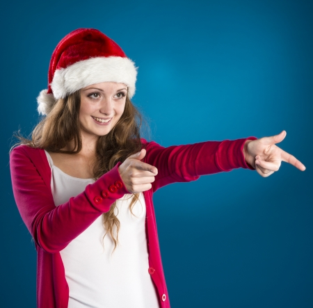 Portrait of attractive woman isolated on blue, studio shot in christmas hatの写真素材