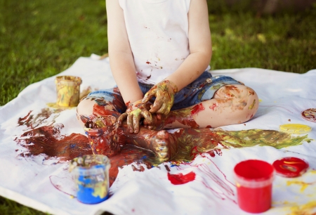 Cute child painting with vibrant colors in the gardenの写真素材