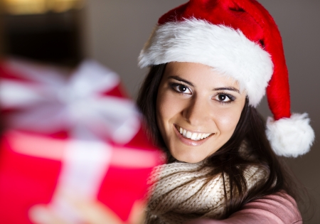 Beautiful dark hair woman opening red christmas giftの写真素材