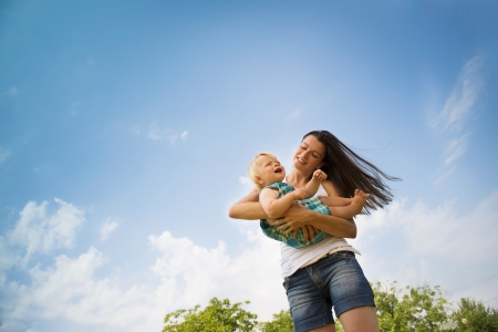Happy young mother playing with her kid in a green fieldの写真素材