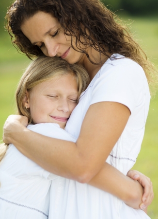 Mother and teenage daughter hugging and smiling together in summer garden の写真素材