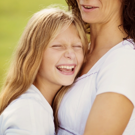 Mother and teenage daughter hugging and smiling together in summer garden の写真素材