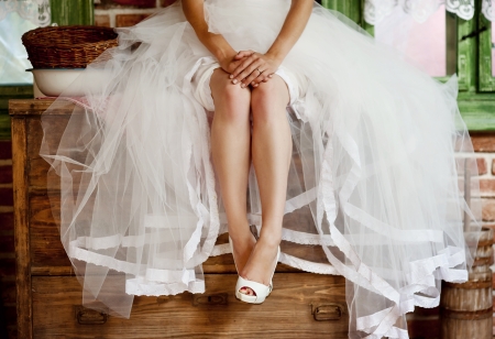 Detail of bridal legs with shoes sitting on the wooden tableの写真素材