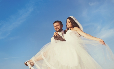 Newly married couple portrait with blue sky in summer fieldの写真素材