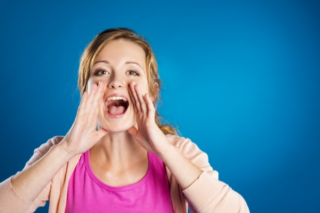 Beautiful young woman posing in studio over a blue backgroundの写真素材