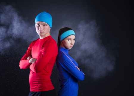 Young fitness athletes are posing in studio with black background  They are dressed in winter sportswear の写真素材