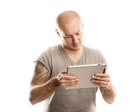 Handsome young man with tattoo is holding digital tablet, isolated on white の写真素材