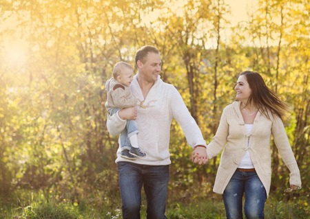 Happy and young family relaxing together in golden and colorful autum natureの写真素材