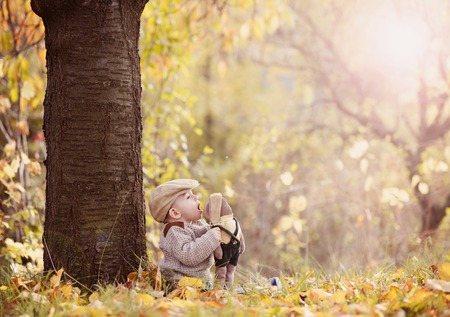 Happy child in warm clothes is playing in colorful autumn natureの写真素材