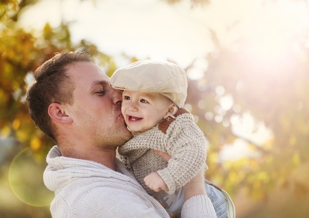 Handsome father relaxing with his son in colorful autumn natureの写真素材