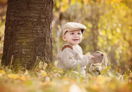 Happy child in warm clothes is playing in colorful autumn natureの写真素材