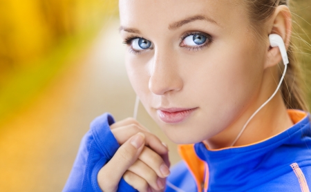 Sporty and active woman runner is listening to music before outdoor exercise